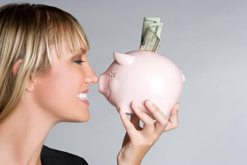 Young woman pressing a savings pig against her nose in relation to rhinoplasty.