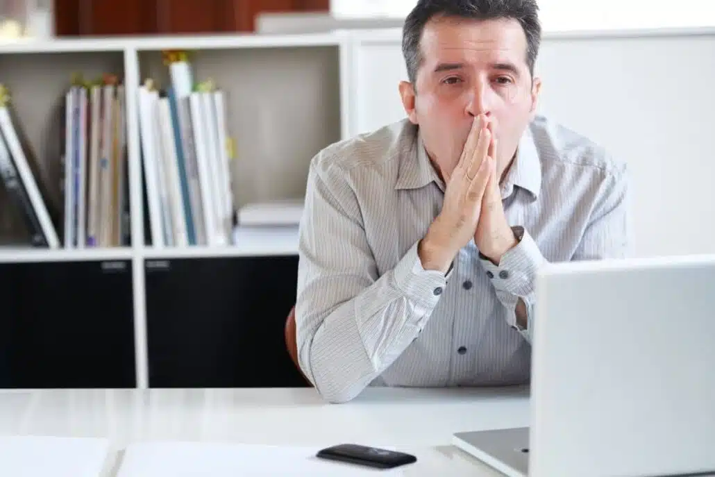 Sleep-deprived man yawning at work, showing daytime fatigue and poor focus from undiagnosed sleep apnea.