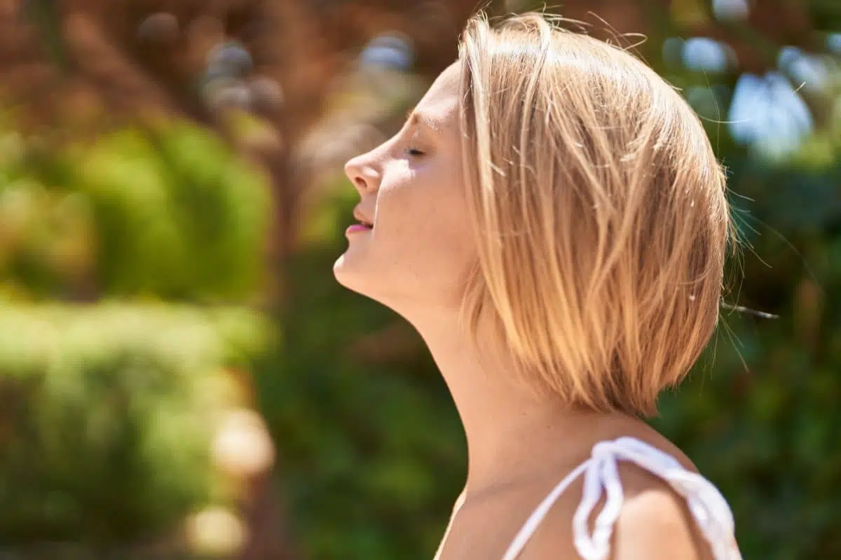Young woman enjoying fresh air with eyes closed, symbolizing clear breathing after successful septorhinoplasty.