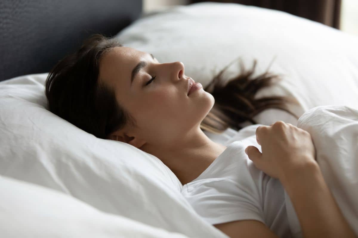 Woman resting on her back with head elevated after rhinoplasty to minimize swelling and support healing.